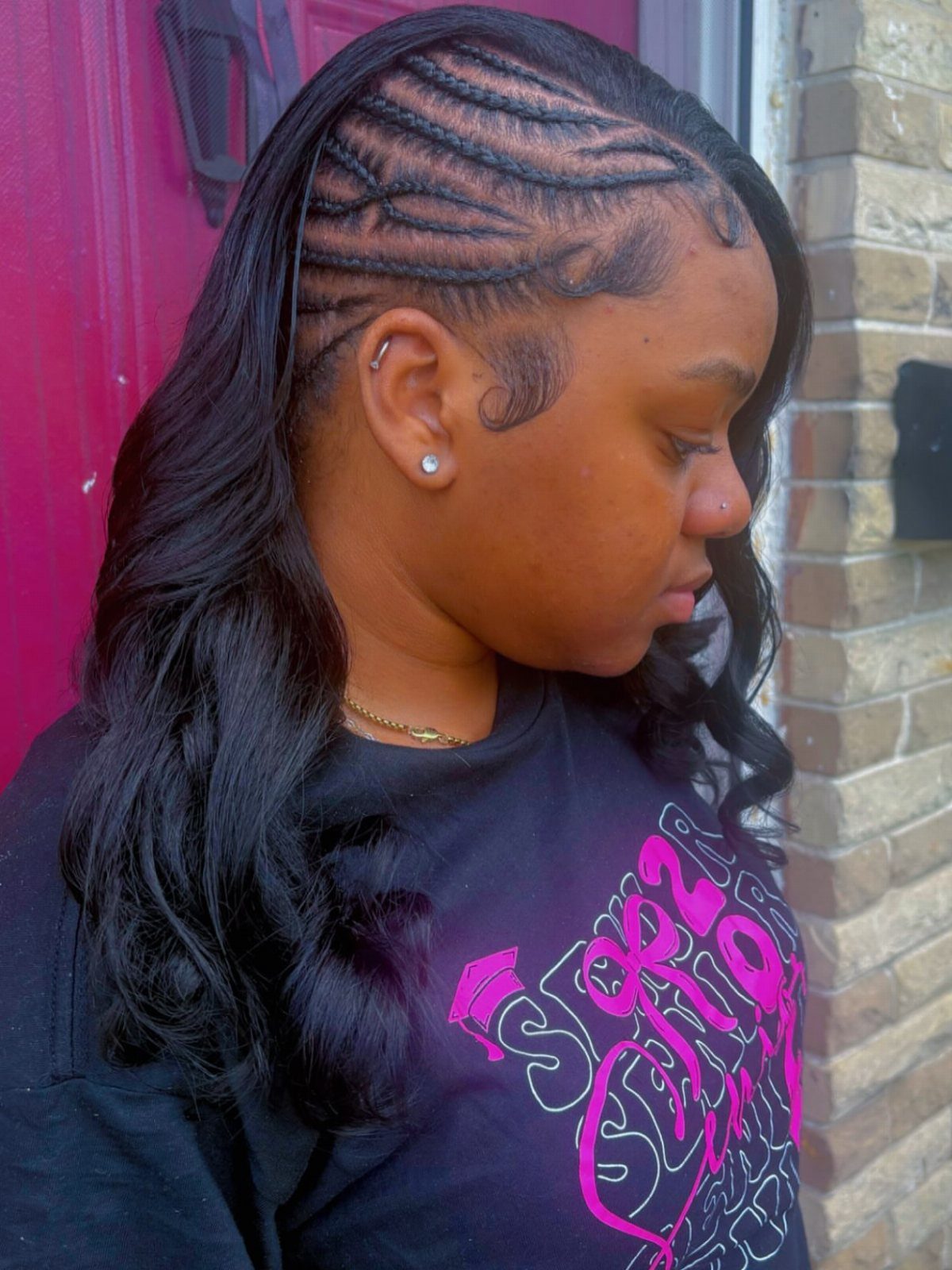 Woman with intricate cornrow braids on the side of her head and long curls.