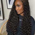 Woman with long dark boho braids and curly ends wearing a black sweatshirt