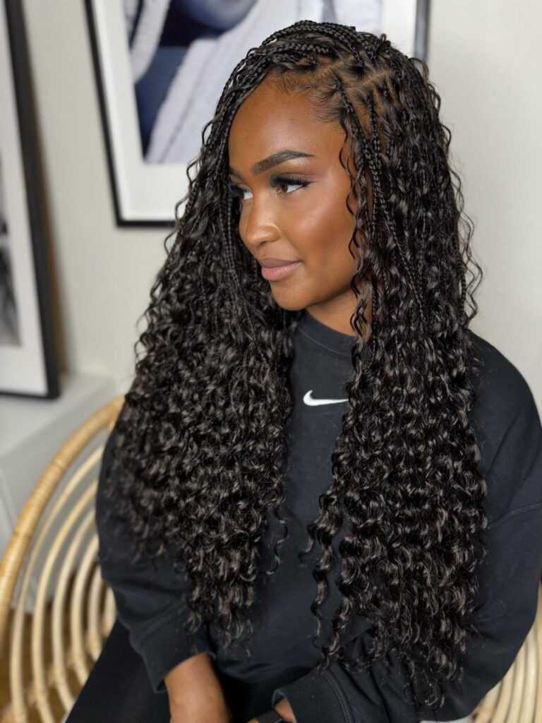 Woman with long dark boho braids and curly ends wearing a black sweatshirt