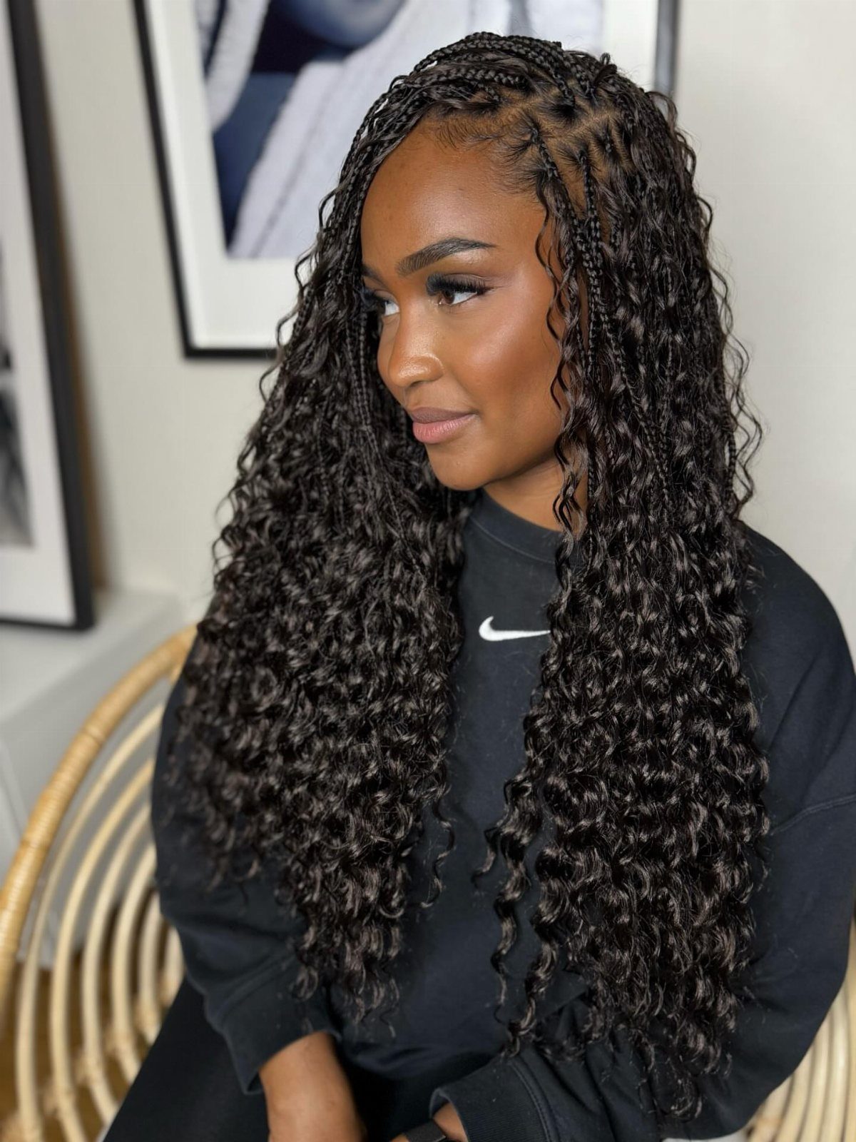 Woman with long dark boho braids and curly ends wearing a black sweatshirt
