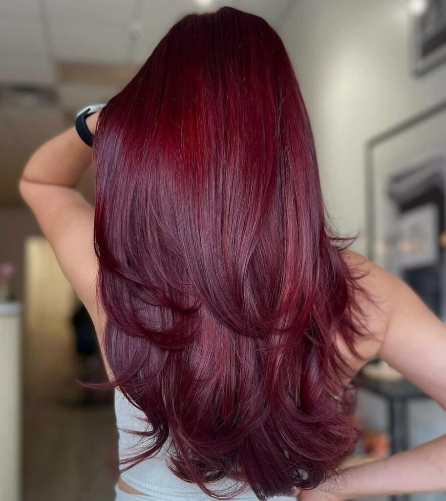 Long layered cherry red hair with a glossy finish seen from behind.