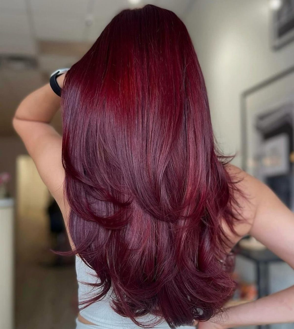 Long layered cherry red hair with a glossy finish seen from behind.
