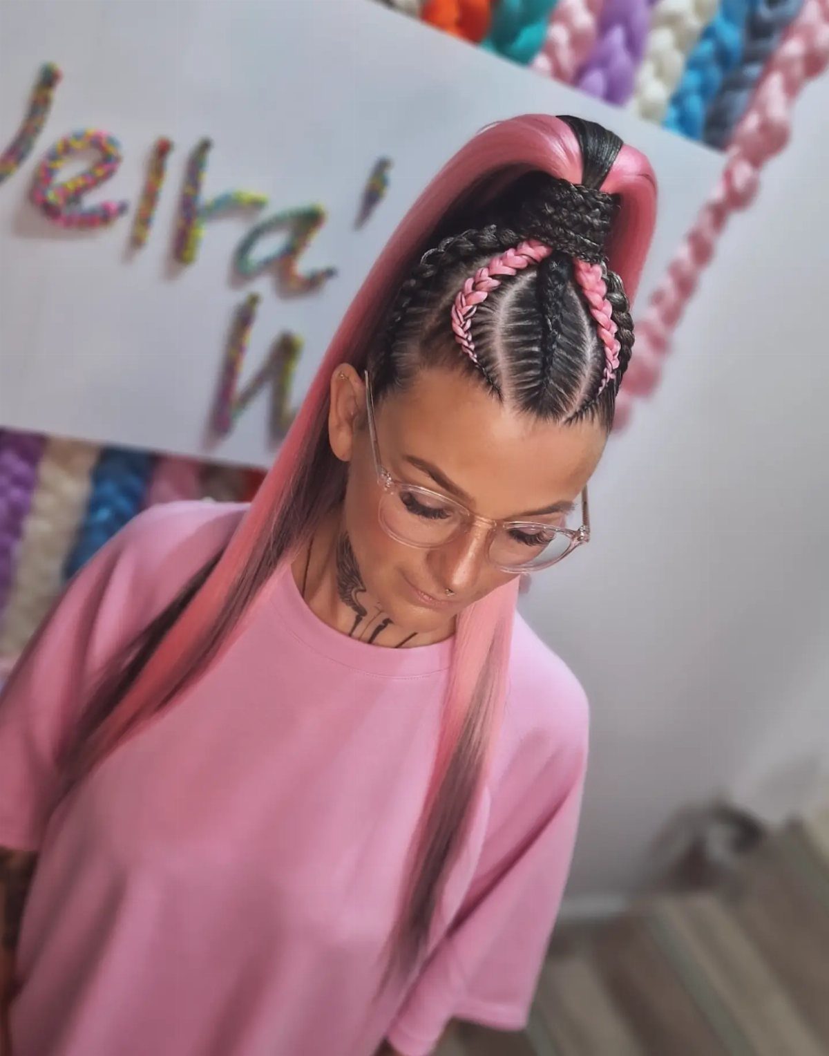 Woman with pink hair featuring cornrow braids tied into a high ponytail.