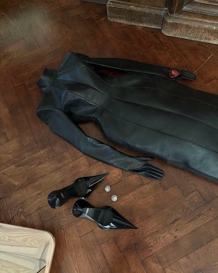 Black leather dress with gloves and pointed heels on a wooden floor