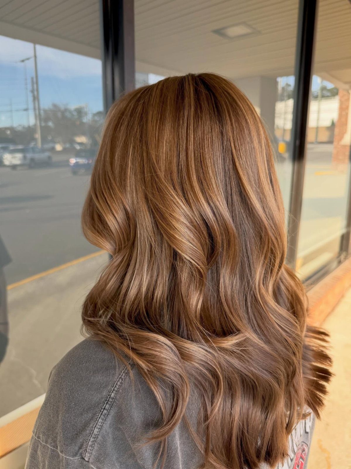 Long wavy brown hair with warm caramel highlights seen from the back.