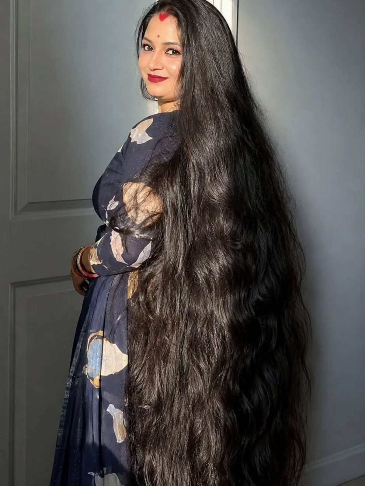 Woman with wavy black hair extending from her head down to the floor.