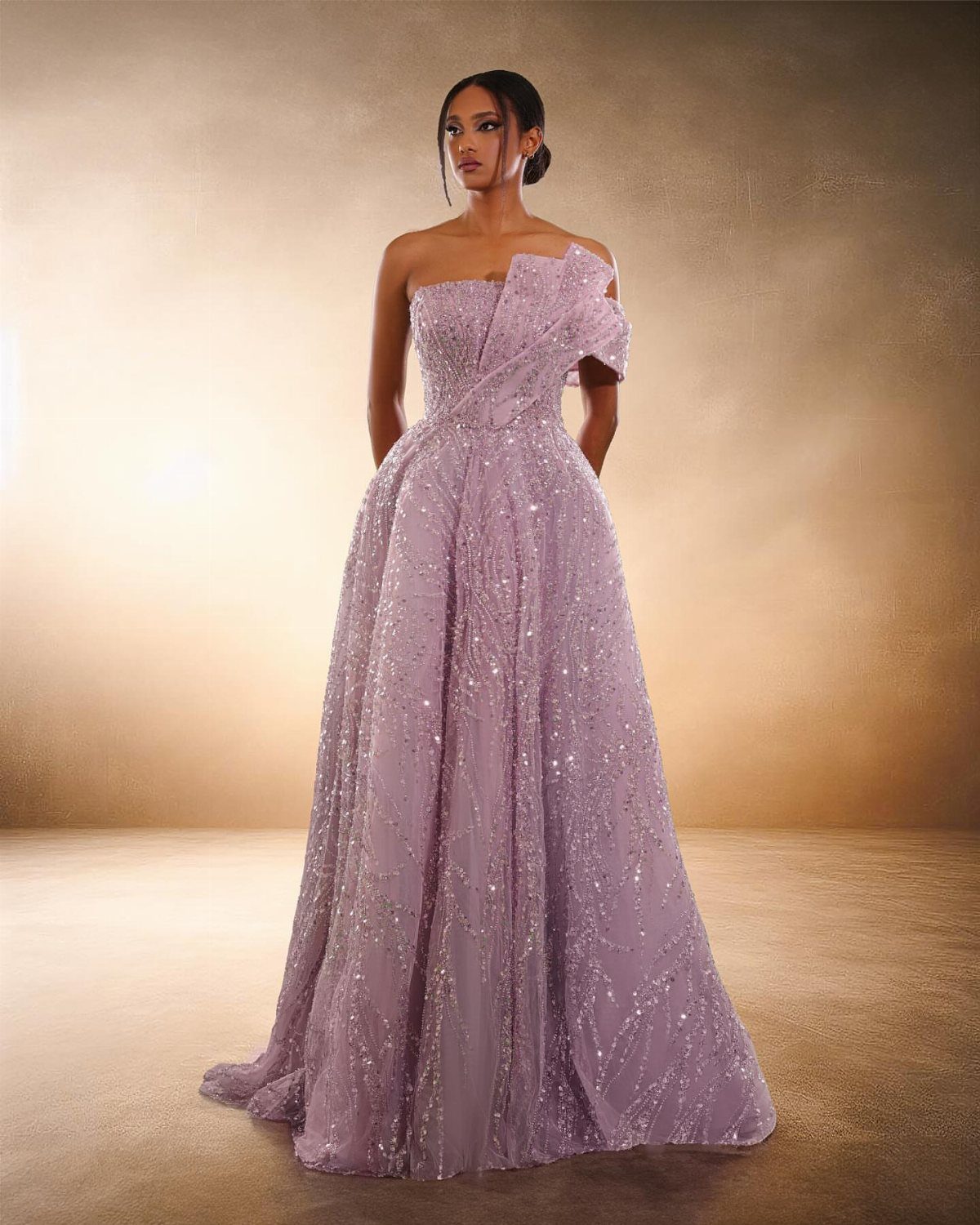Woman in a shimmering lavender one-shoulder haute couture evening dress against a neutral background
