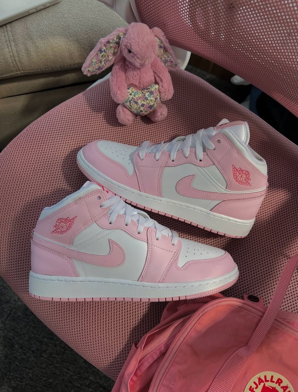 Pink and white Jordan sneakers with a plush bunny on a pink surface.