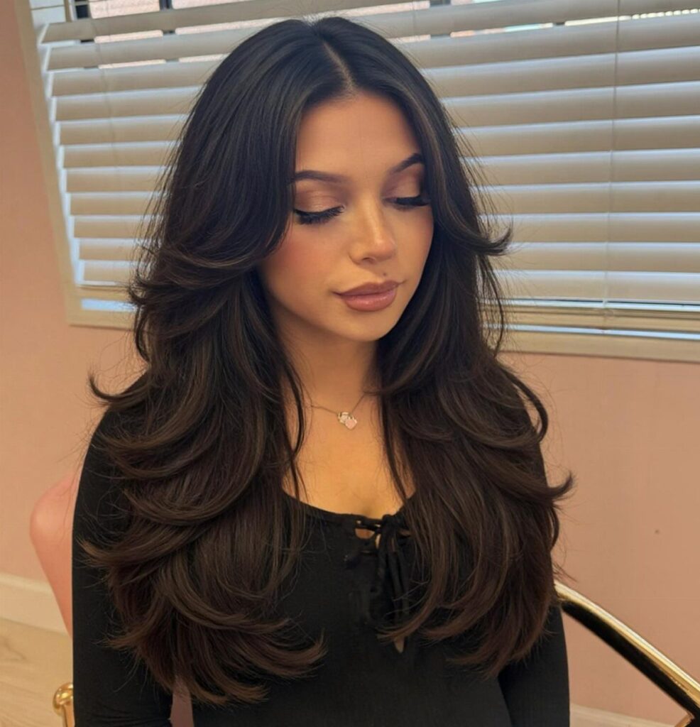 Woman with long dark brown hair styled in a voluminous layered blowout haircut.