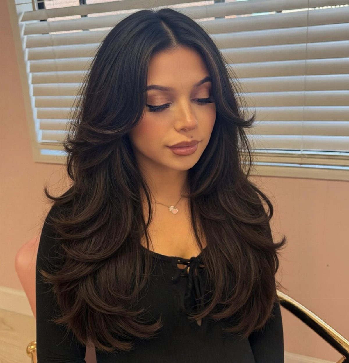 Woman with long dark brown hair styled in a voluminous layered blowout haircut.