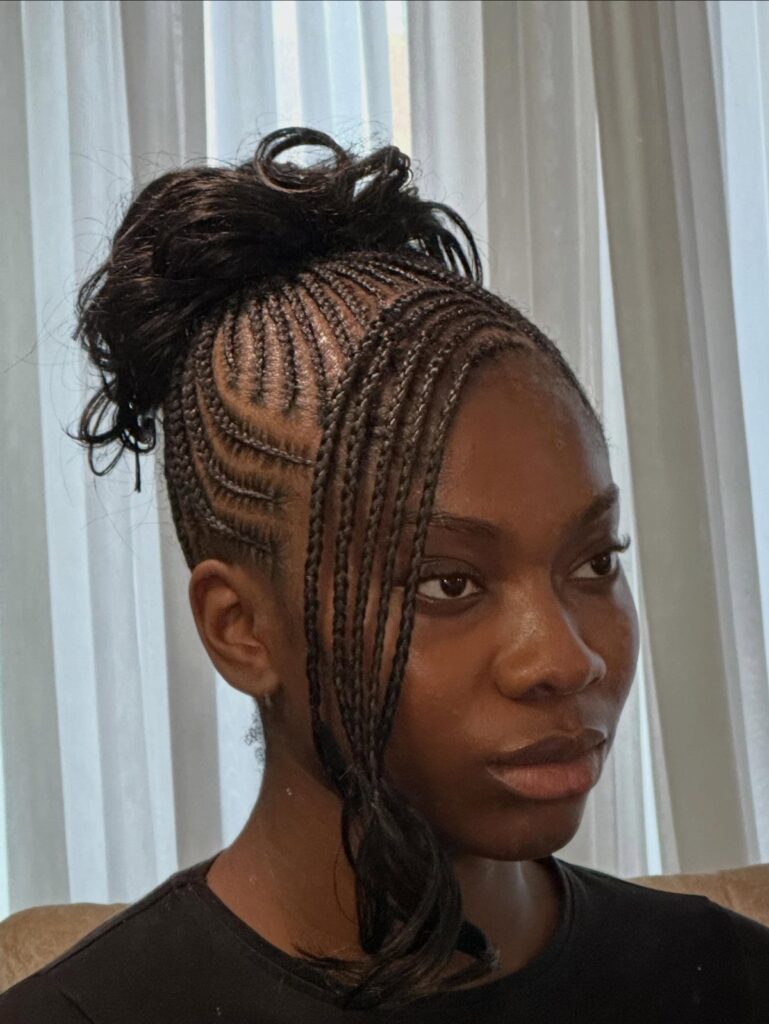 Woman with cornrow braids styled into a messy bun on top of her head