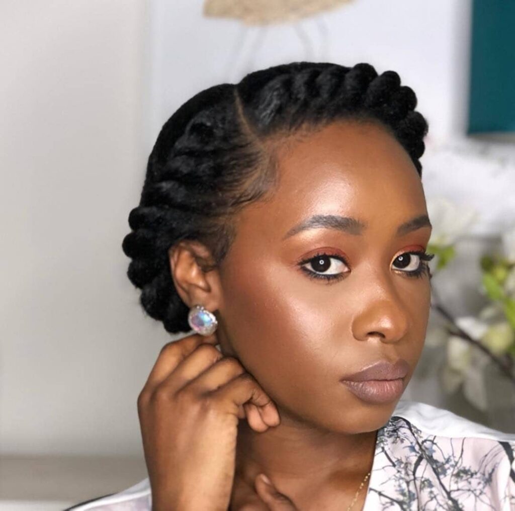 Black woman with natural black hair styled in a twisted updo and makeup.