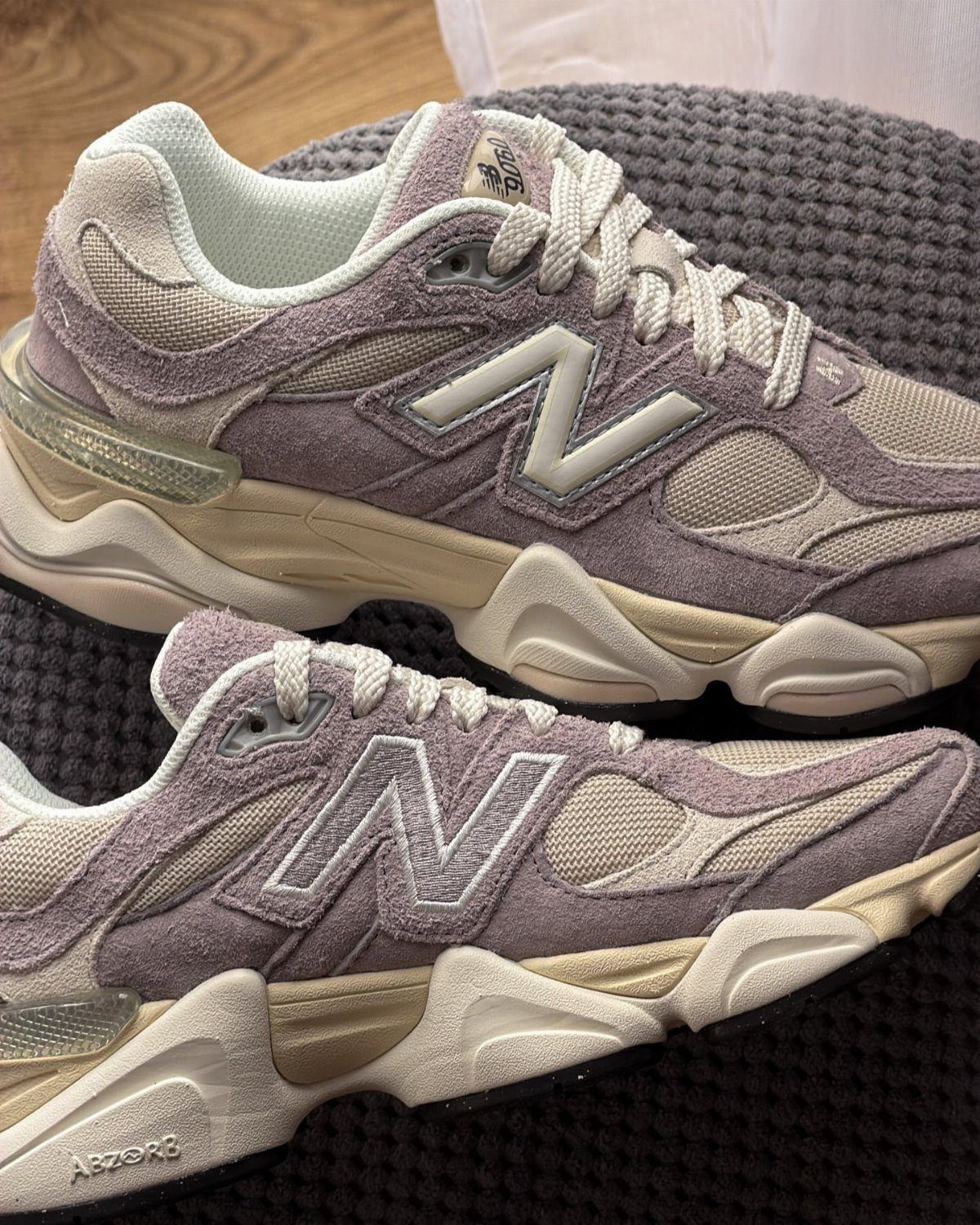 New Balance 9060 sneakers in truffle and purple on a grey textured background
