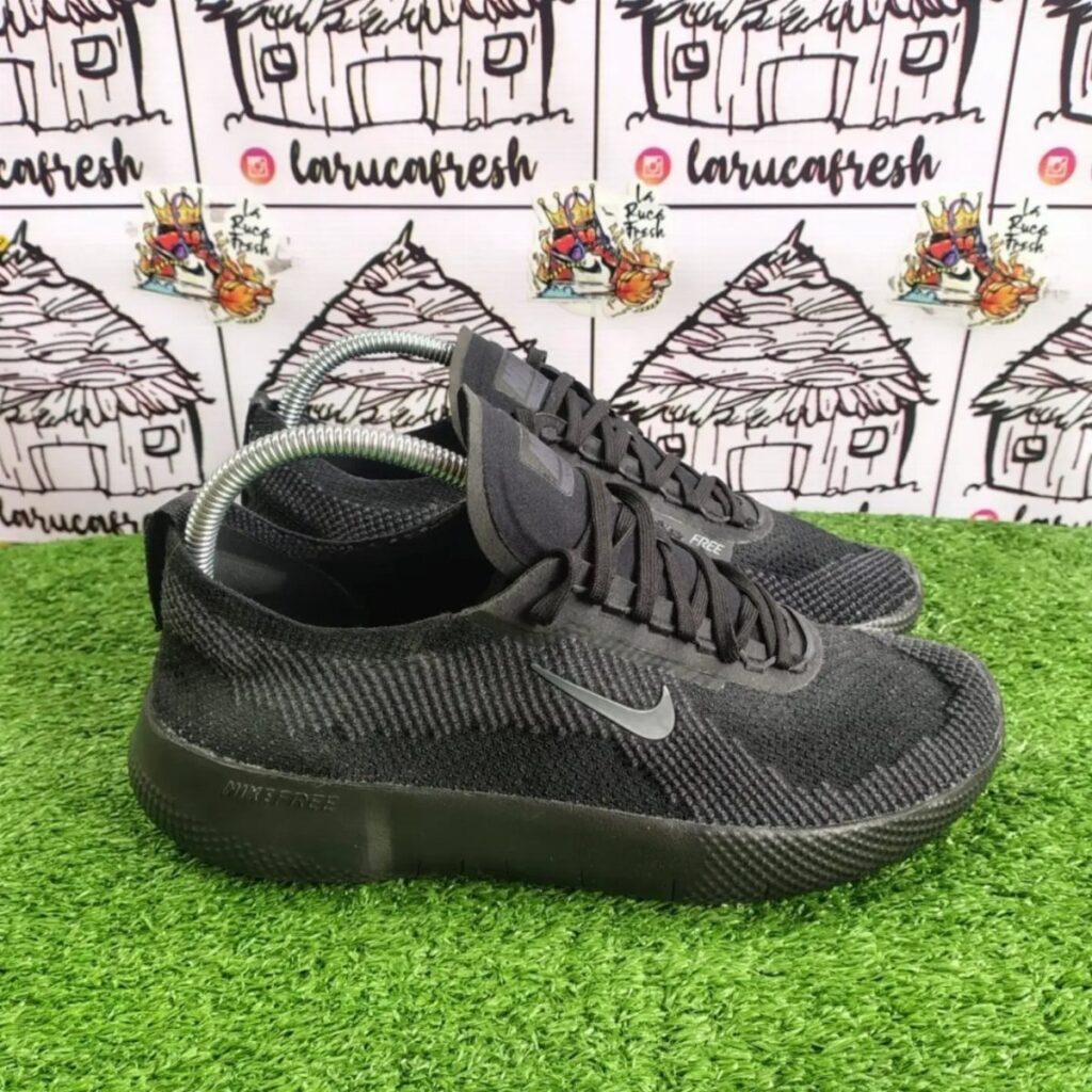 Black Nike Free sneakers with grey swoosh on green artificial grass background