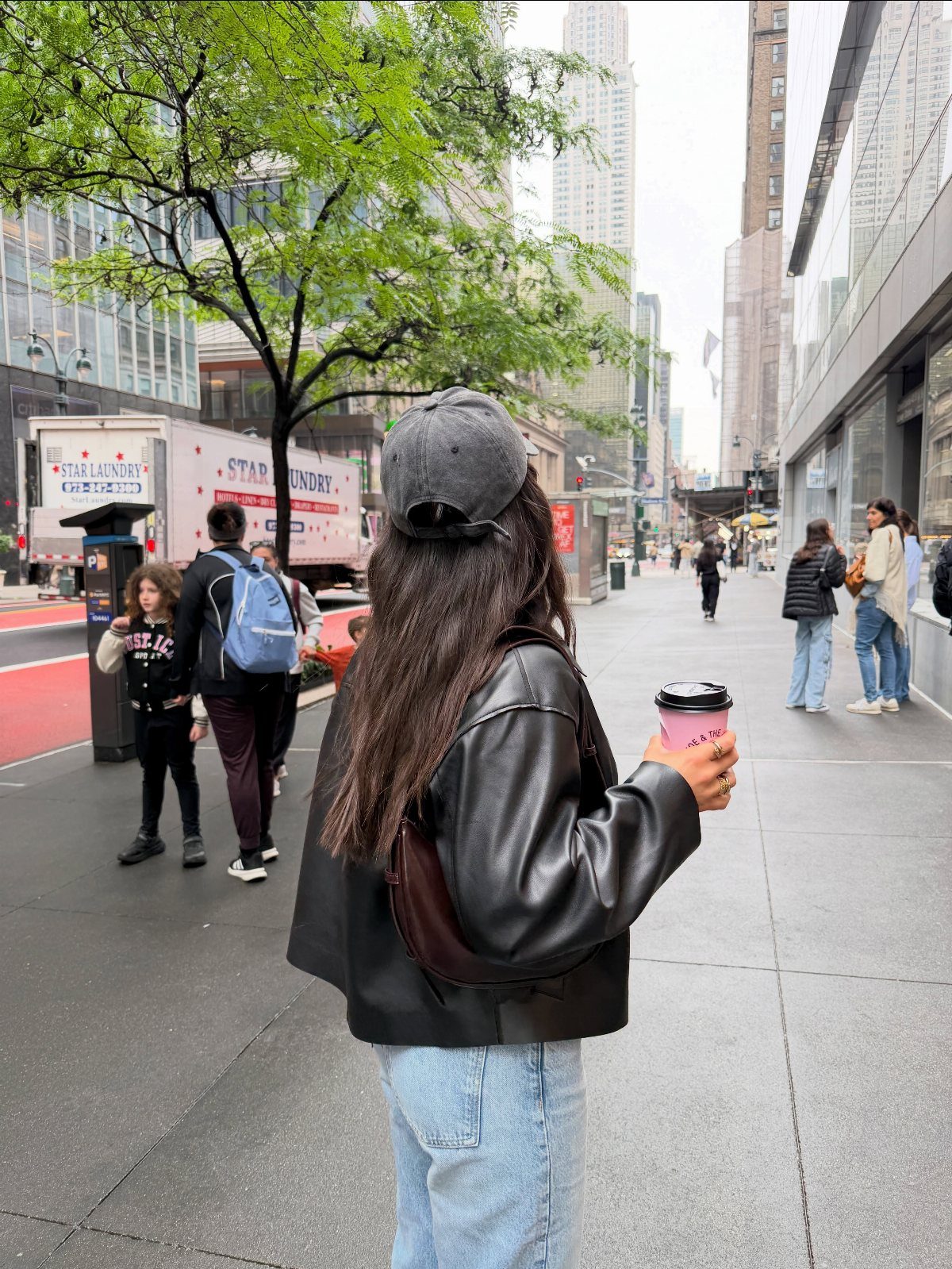 Person in leather jacket and jeans walking on a New York City sidewalk