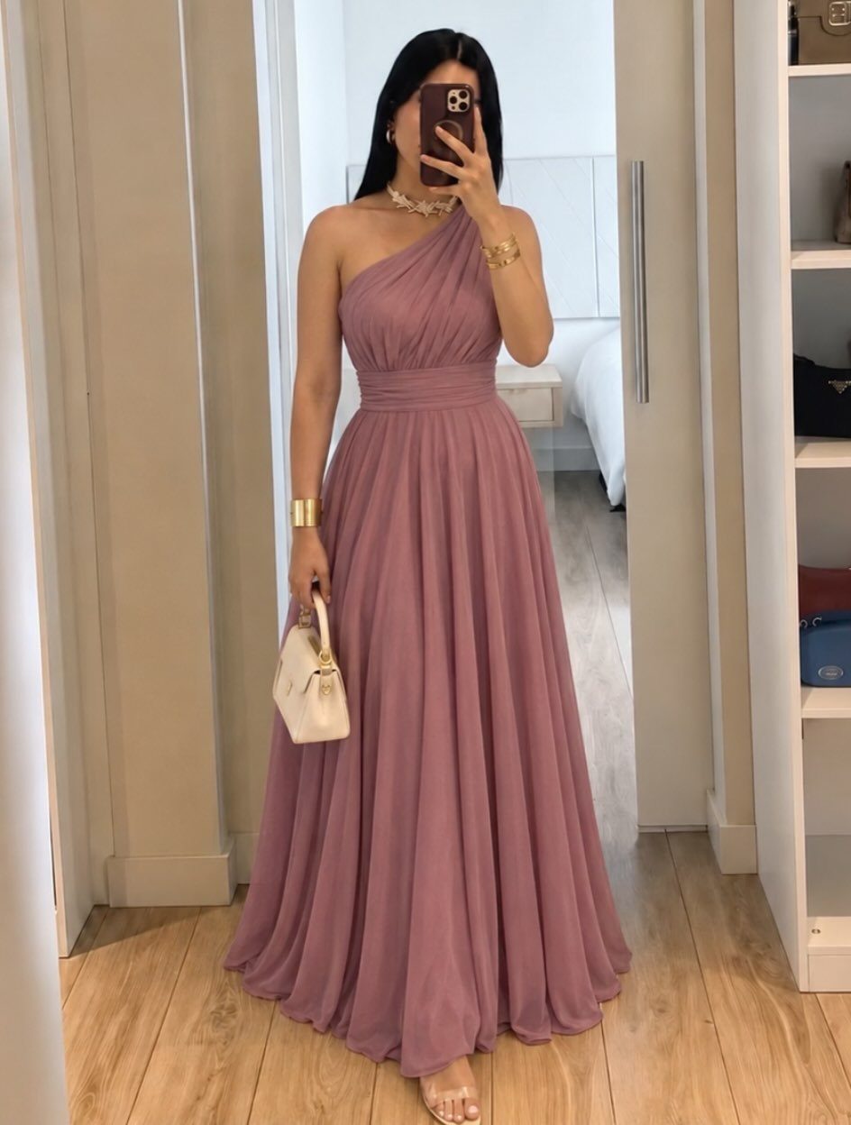 Woman in a one-shoulder mauve semi formal gown holding a white handbag.