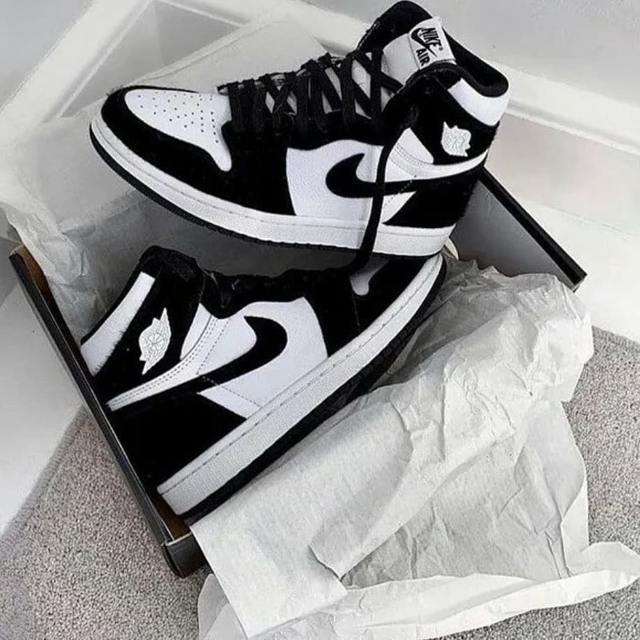 Black and white Air Jordan high-top sneakers inside a box with white tissue paper.