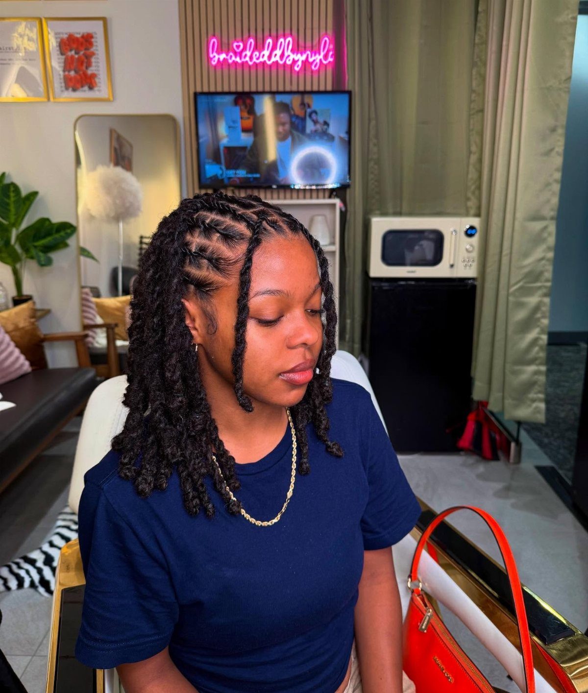 Woman with two strand twist hairstyle wearing a navy blue t-shirt and gold chain.